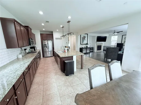 a large living room with stainless steel appliances granite countertop couches a fireplace a flat screen tv and a kitchen island