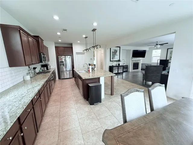 a large living room with stainless steel appliances granite countertop couches a fireplace a flat screen tv and a kitchen island