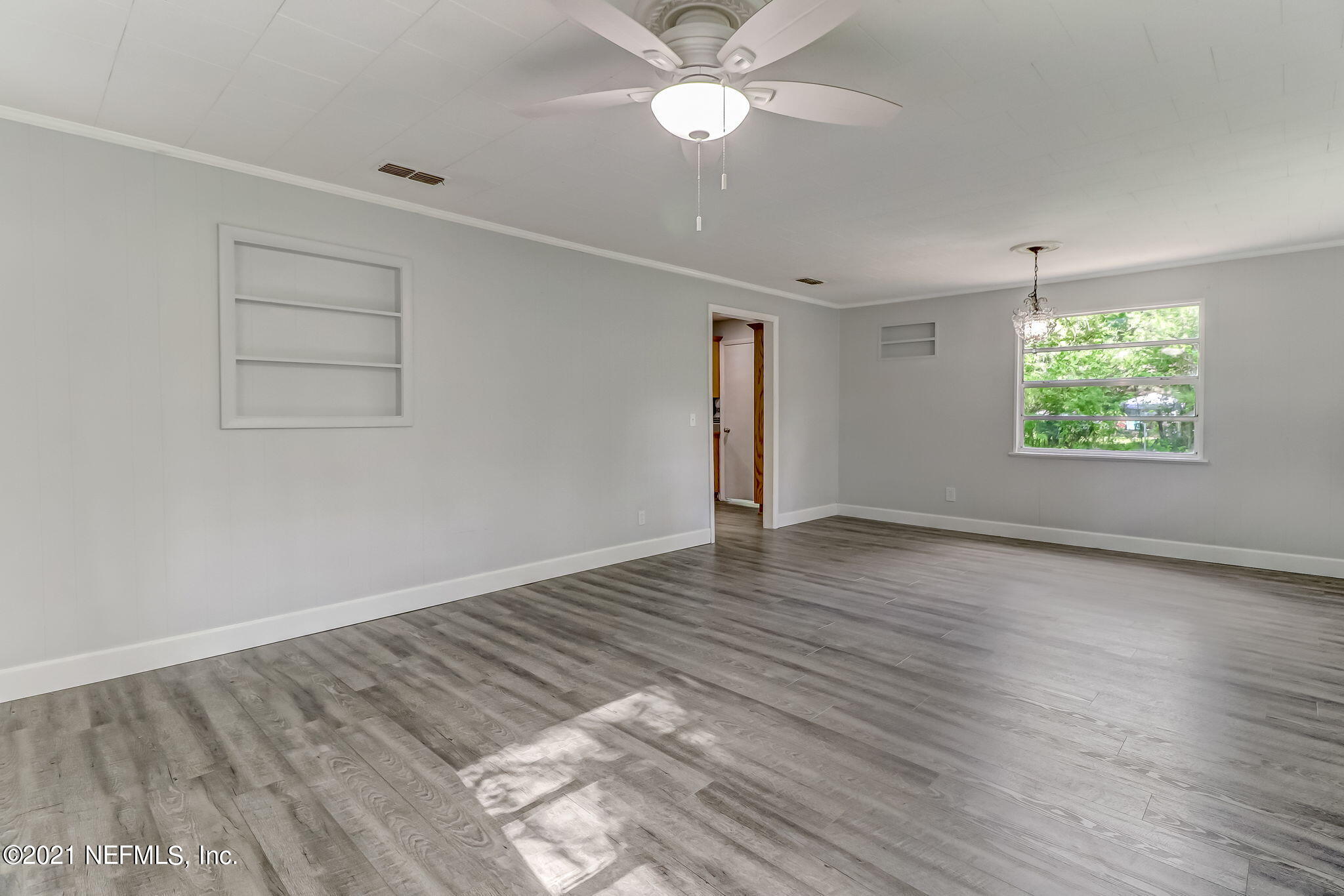 541754 Lem Turner Road Callahan, FL 32011 - Photo 8 of 27 an empty room with wooden floor chandelier fan and windows