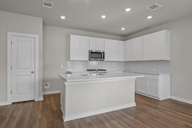 a kitchen with kitchen island a sink and a stove top oven