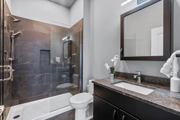 a bathroom with a granite countertop sink toilet mirror and shower