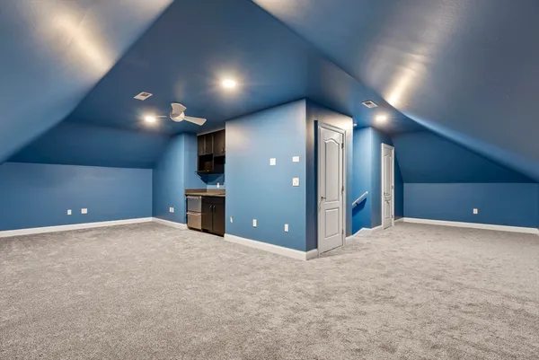 a view of an empty room with kitchen and fireplace