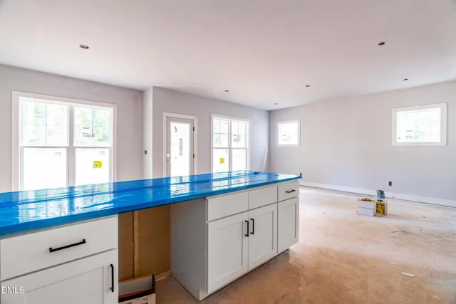 a kitchen with white cabinets and window
