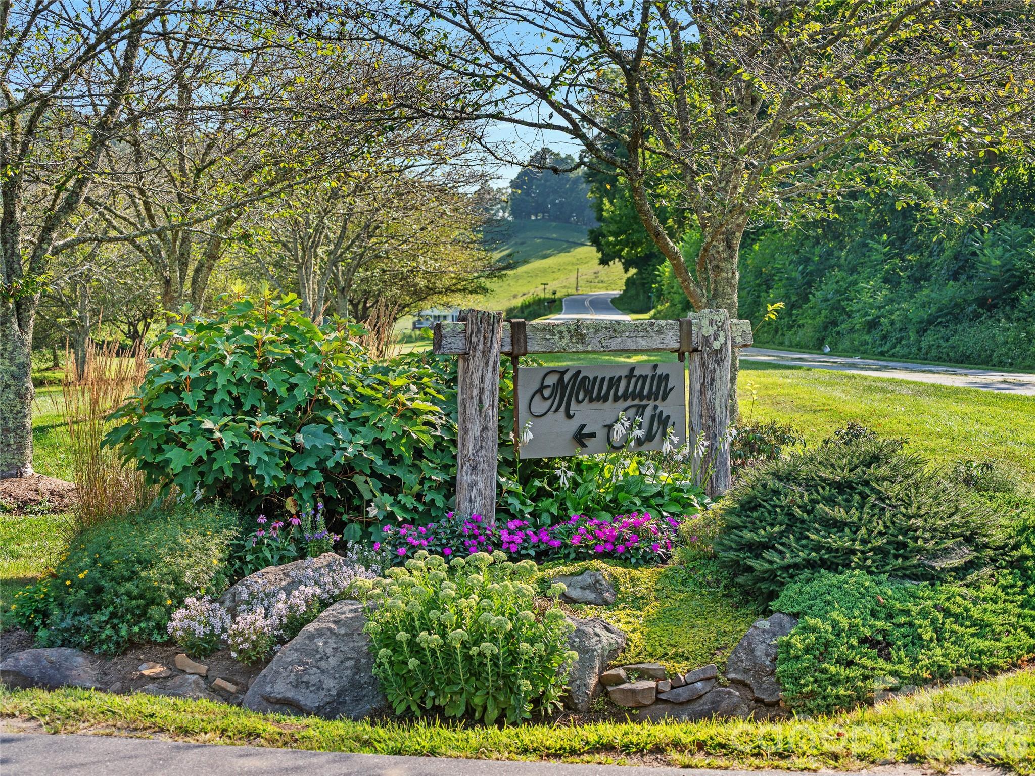 Lot 4 Heritage Ridge Road Burnsville, NC 28714 - Photo 17 of 28 a view of a sign board with flower plants and large trees