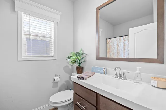a bathroom with a granite countertop toilet sink and mirror