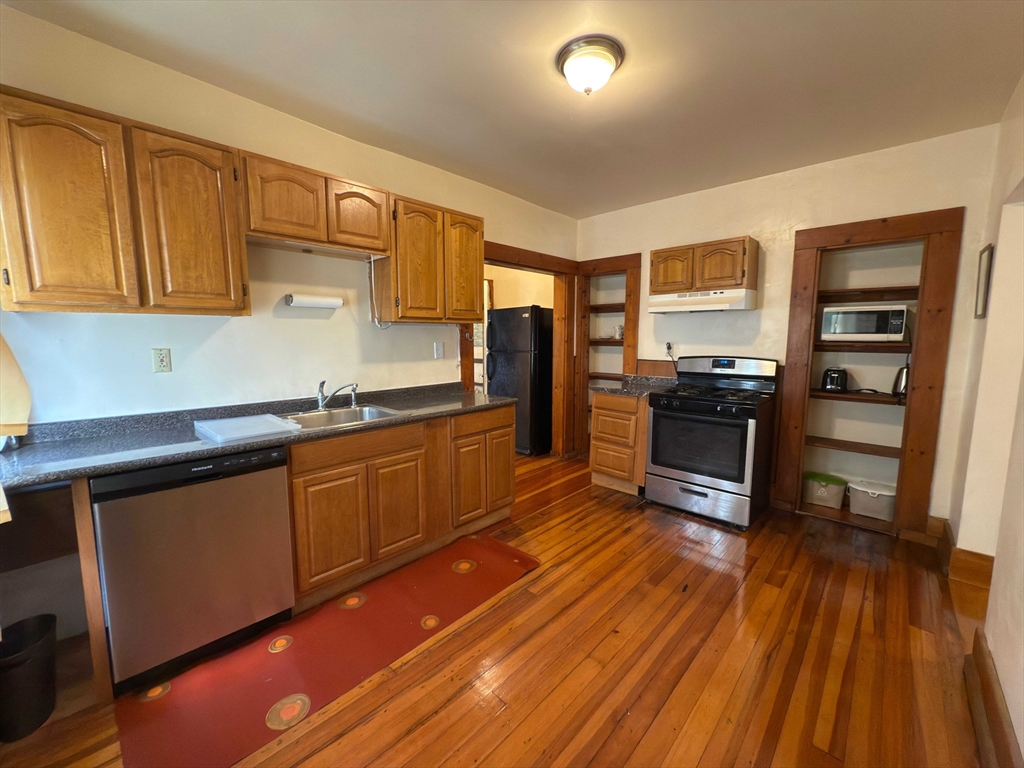 3965 Washington Street Boston, MA 02131 - Photo 5 of 18 a kitchen with stainless steel appliances wooden floors and wooden cabinets