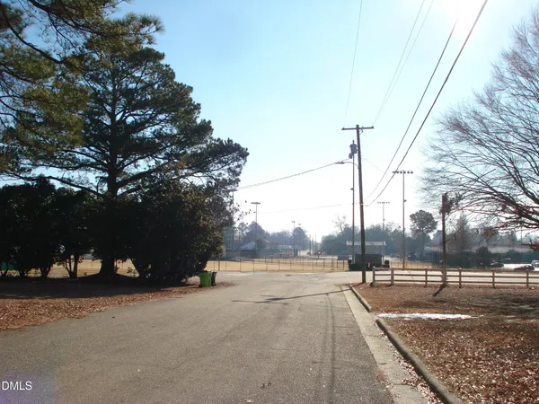 a view of a street with a yard and trees