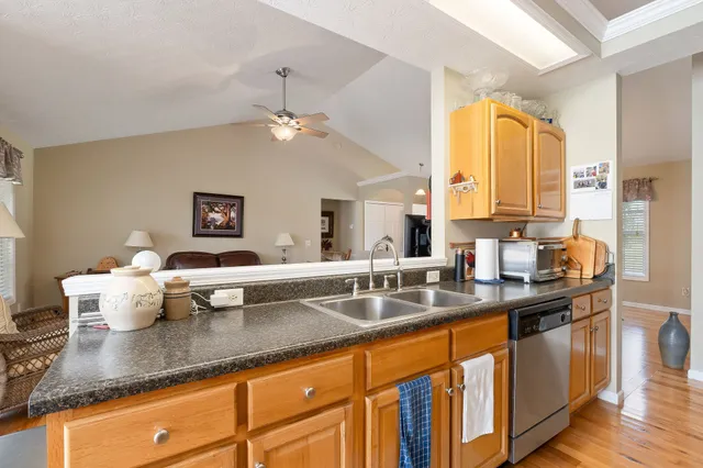 a kitchen with stainless steel appliances granite countertop a sink dishwasher a stove and white cabinets with wooden floor