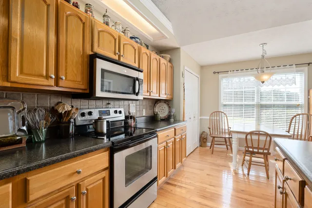 a kitchen with stainless steel appliances granite countertop a stove a sink a dining table and chairs