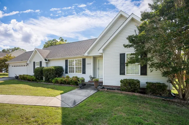 a view of a house with a big yard plants and large trees