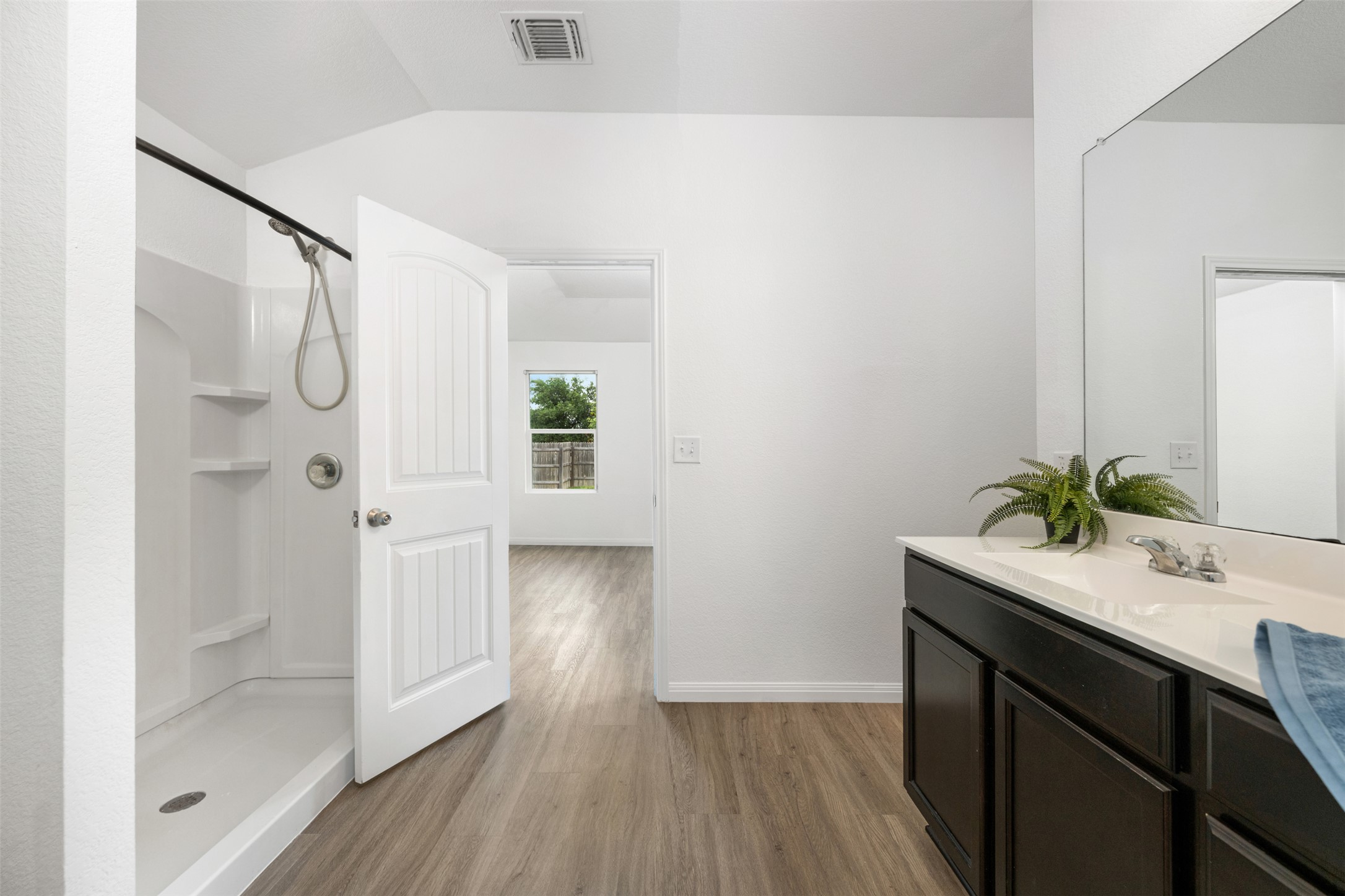 14900 Retha Pass Austin, TX 78725 - Photo 17 of 39 Bathroom featuring a single-sink vanity with dark cabinetry, integrated countertop, and an expansive wall mirror