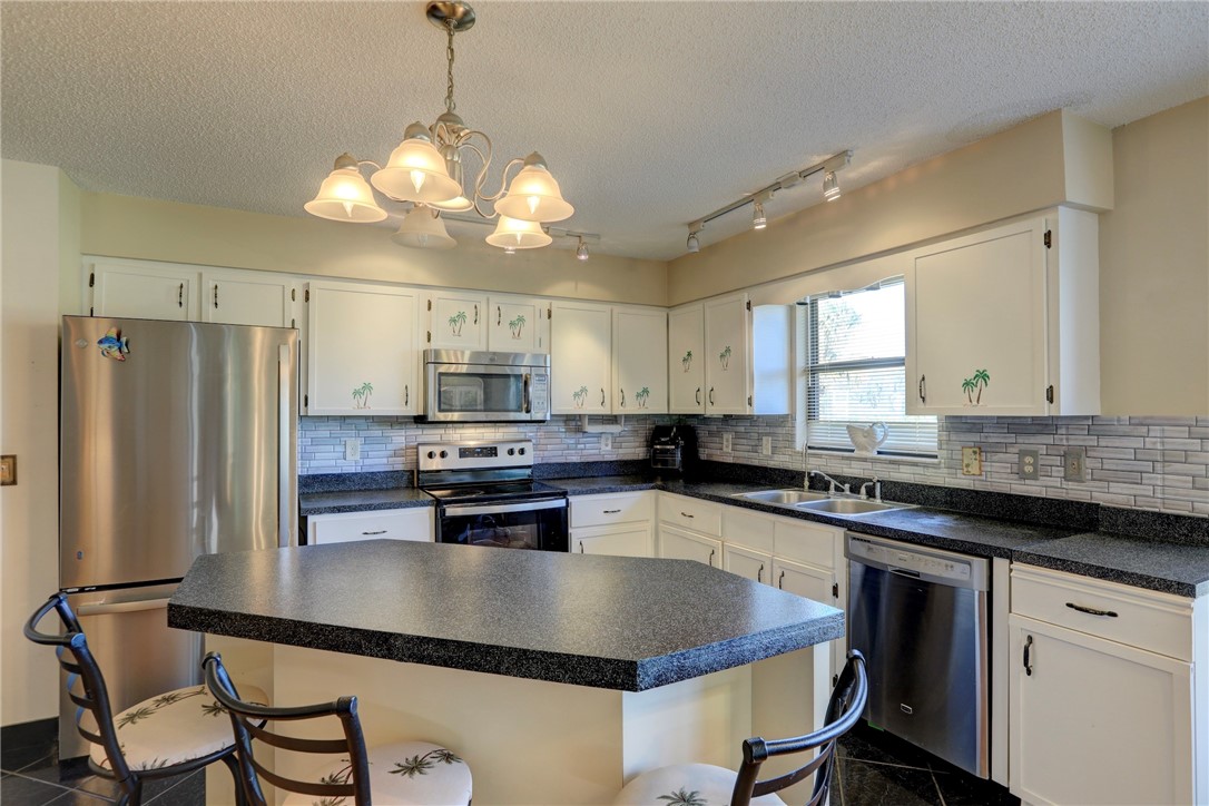 8205 Capewell Court Sebastian, FL 32958 - Photo 8 of 25 a kitchen with stainless steel appliances granite countertop a sink a stove a refrigerator cabinets and chairs