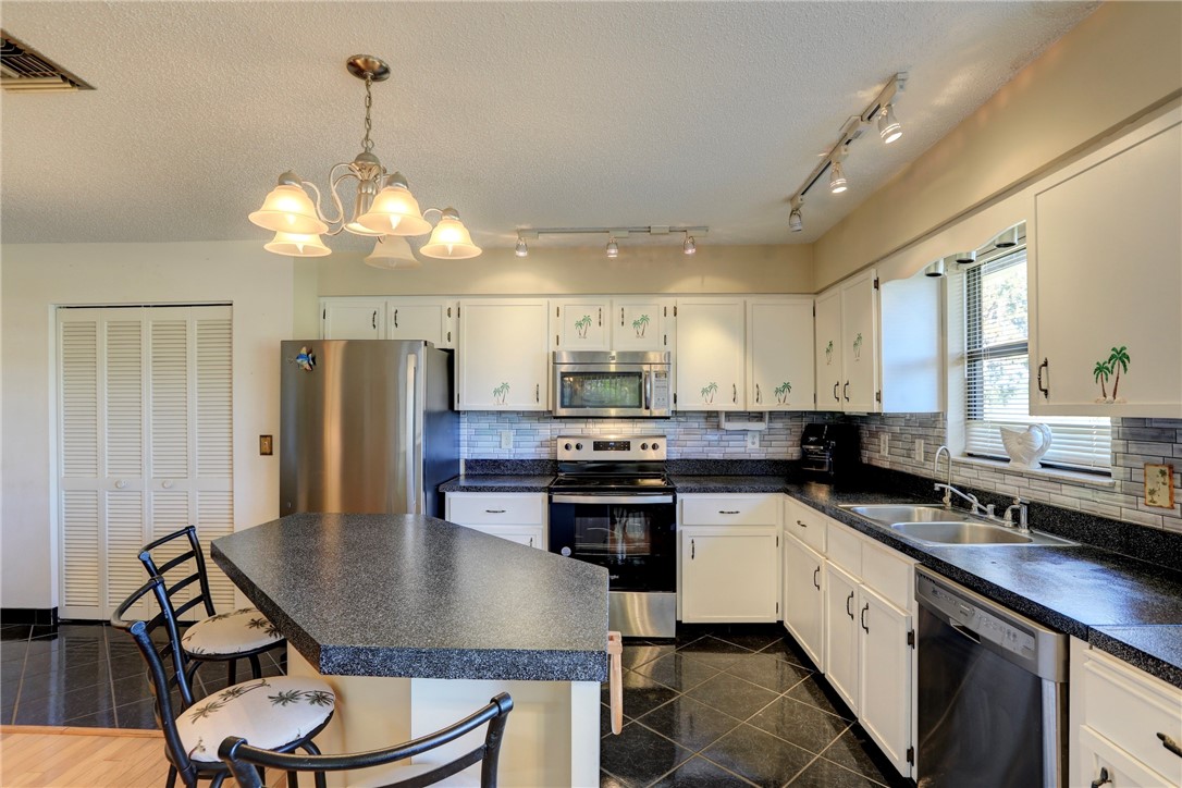 8205 Capewell Court Sebastian, FL 32958 - Photo 9 of 25 a kitchen with stainless steel appliances granite countertop a sink a stove a refrigerator cabinets and dining table