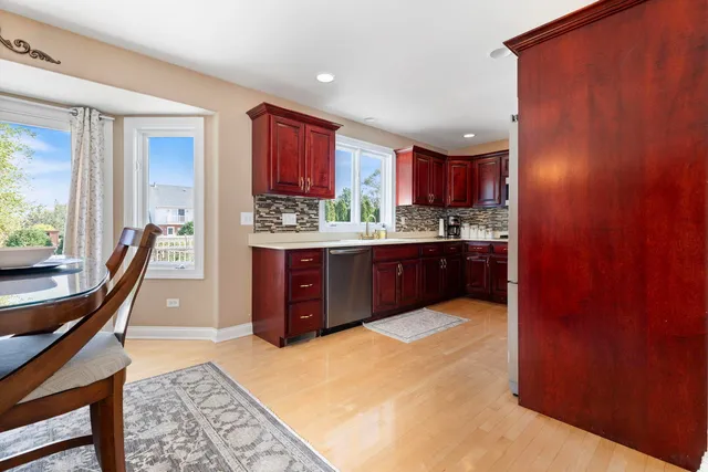 a kitchen with stainless steel appliances granite countertop a stove a sink dishwasher and a refrigerator with wooden cabinets