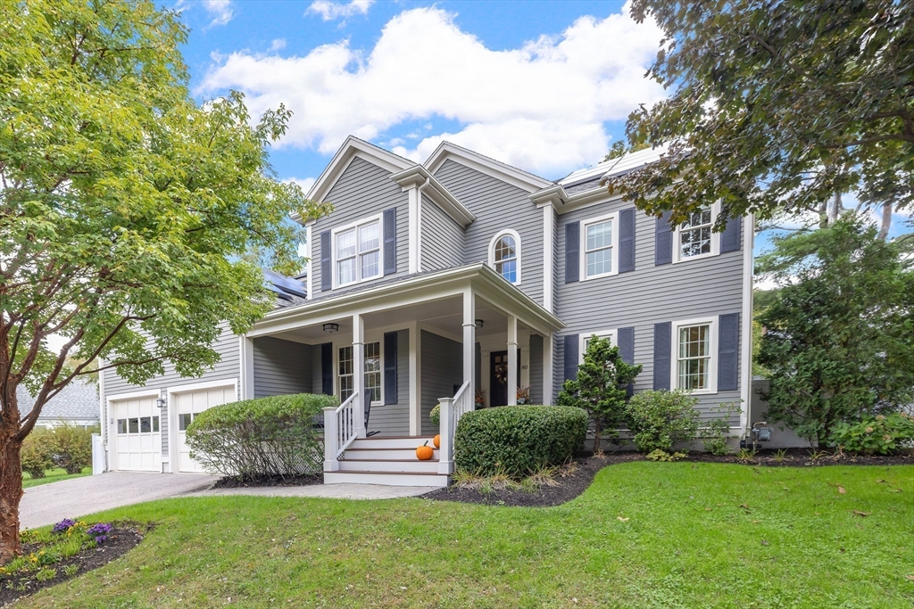a view of a white house next to a yard with plants and trees