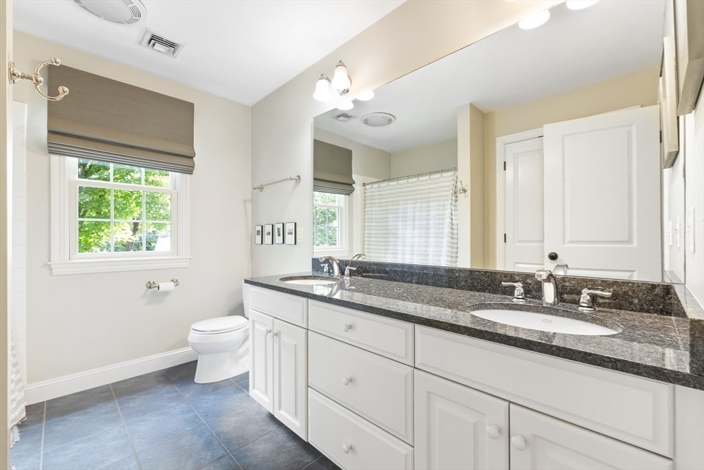 80 Emerson Road Needham, MA 02492 - Photo 28 of 41 a bathroom with a granite countertop double vanity sink a mirror and a toilet