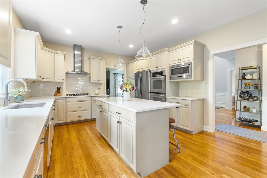 80 Emerson Road Needham, MA 02492 - Photo 7 of 41 a kitchen with stainless steel appliances kitchen island granite countertop a stove a sink a refrigerator and white cabinets with wooden floor