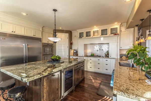 a very nice looking dining room with kitchen island granite countertop a table chairs and a chandelier