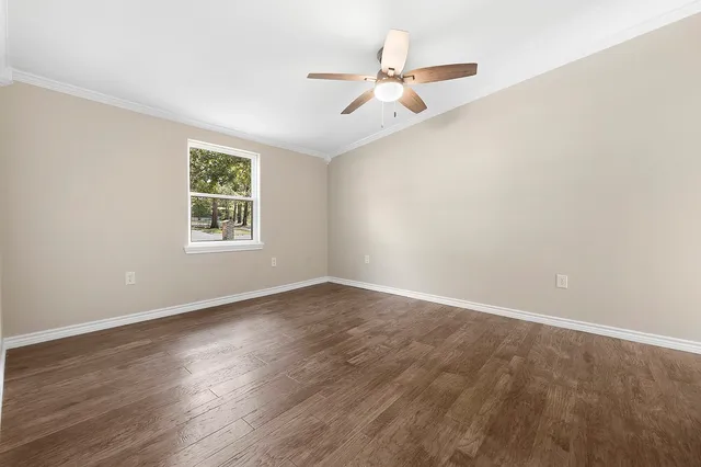 an empty room with wooden floor fan and windows