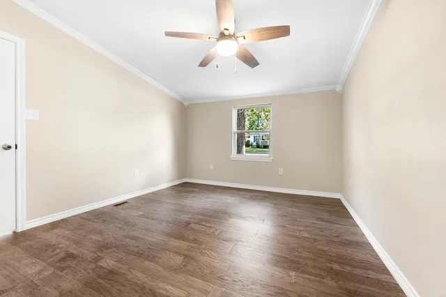 an empty room with windows and ceiling fan