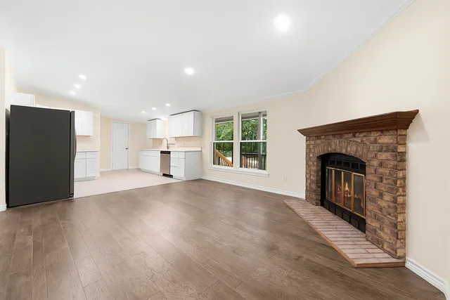 an empty room with wooden floor fireplace and windows