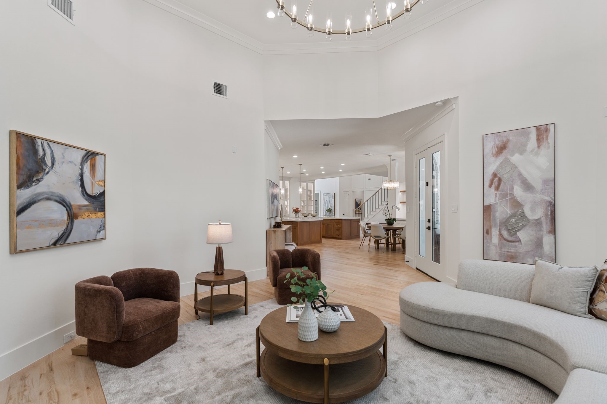 31 Hollymead Drive Spring, TX 77381 - Photo 19 of 50 This inviting family area features high ceilings and a modern chandelier. It seamlessly opens into the spacious kitchen and breakfast area, creating an airy and cohesive living space perfect for entertaining.