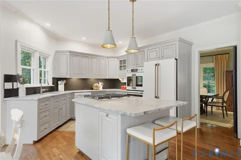 a kitchen with stainless steel appliances granite countertop a stove a refrigerator a sink dishwasher and white cabinets with wooden floor