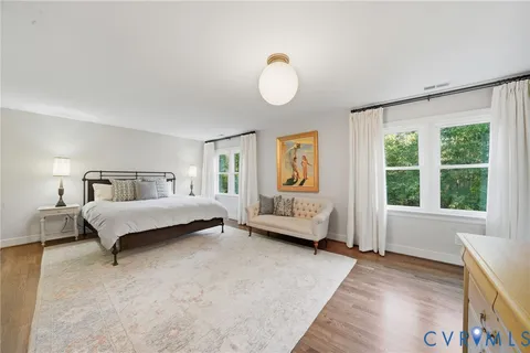 a spacious bedroom with a bed and wooden floor