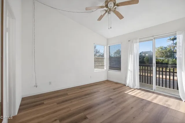 an empty room with wooden floor fan and windows