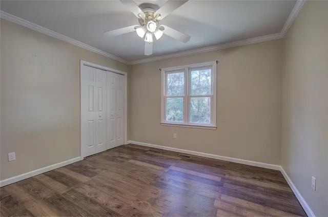 an empty room with wooden floor chandelier fan and windows