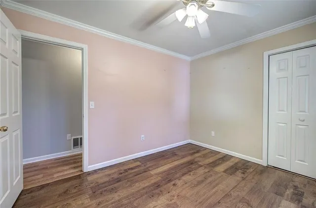 a view of an empty room with wooden floor and a ceiling fan