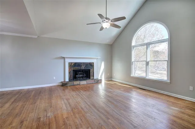 an empty room with wooden floor fireplace and windows