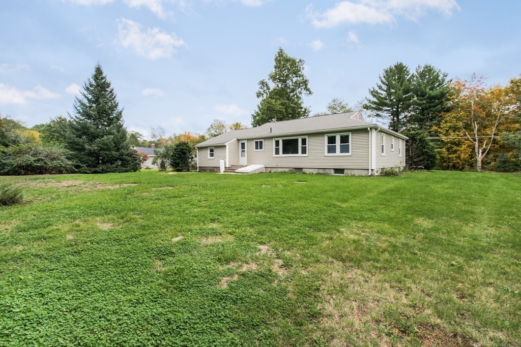 654 North Brookfield Road Oakham, MA 01068 - Photo 25 of 28 a house that is sitting in the grass with large trees and plants