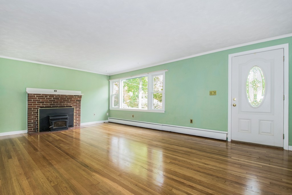 654 North Brookfield Road Oakham, MA 01068 - Photo 10 of 28 an empty room with wooden floor fireplace and windows
