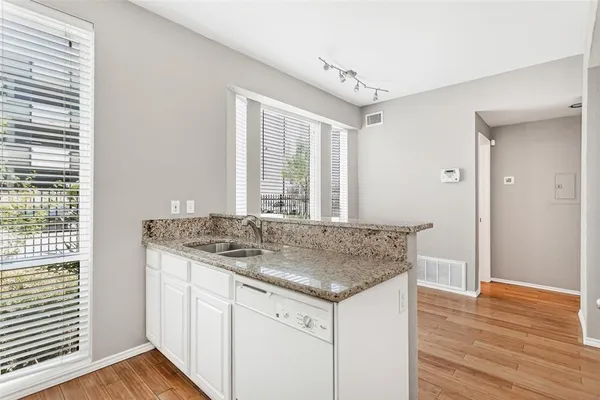 a room with kitchen island granite countertop wooden floor and a sink