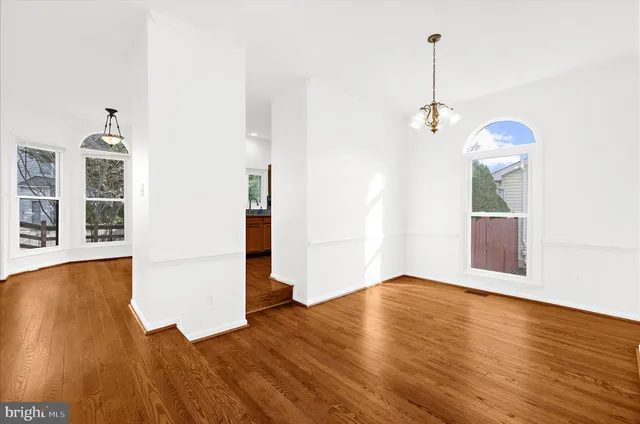 a view of an empty room with wooden floor and a fireplace