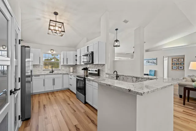 a view of a hallway with wooden floor and a kitchen