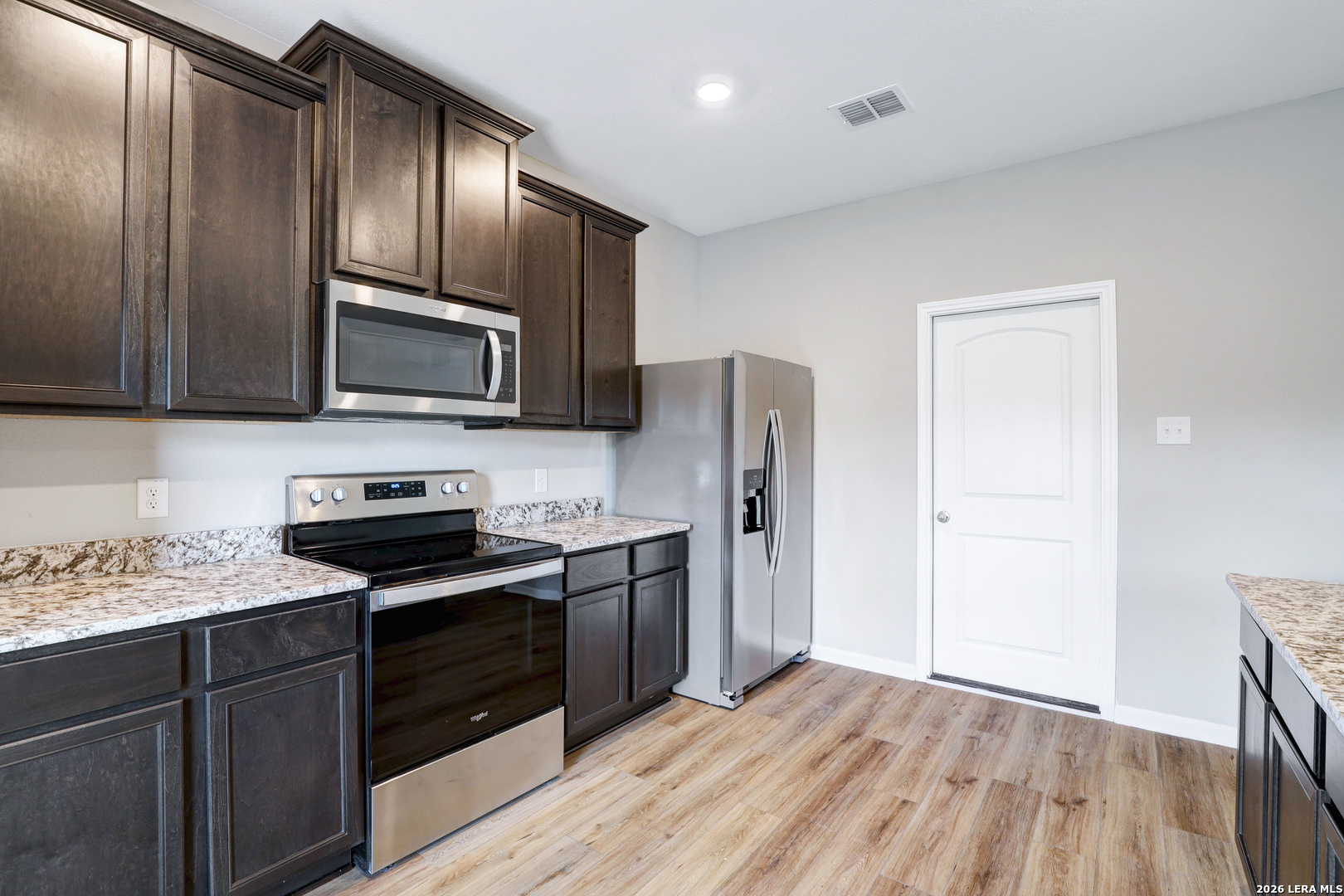 6403 Warhol Cape Converse, TX 78109 - Photo 15 of 29 a kitchen with granite countertop wooden cabinets stainless steel appliances and a wooden floor