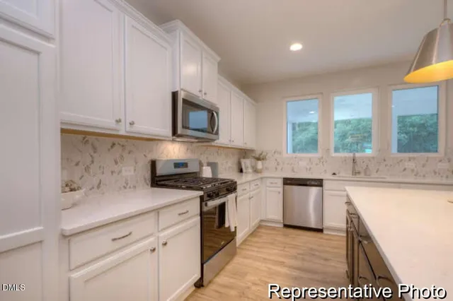 a kitchen with granite countertop a sink a stove and cabinets