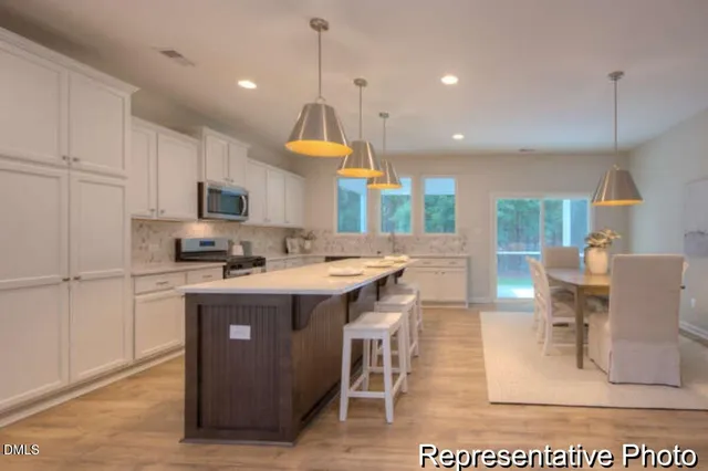 a kitchen with stainless steel appliances granite countertop a stove a sink a oven a dining table and chairs with wooden floor