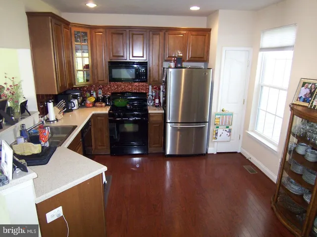 a kitchen with a refrigerator and wooden floor