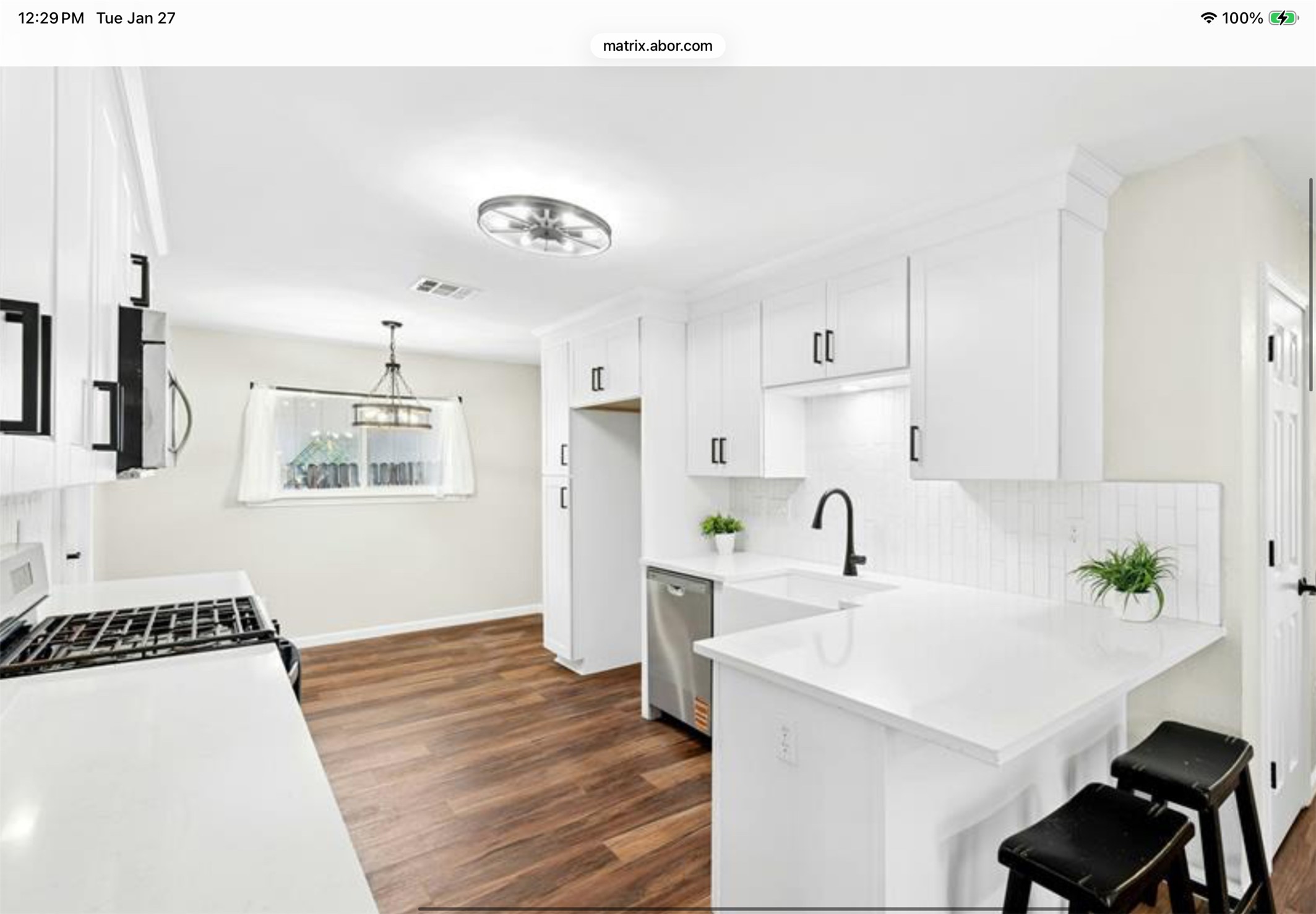 12904 Garfield Lane Austin, TX 78727 - Photo 15 of 31 Kitchen featuring white cabinets, stainless steel appliances, LVP wood finished floors, a kitchen breakfast bar/peninsula.