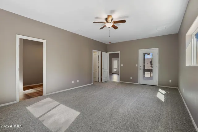 a view of an empty room with chandelier fan and window