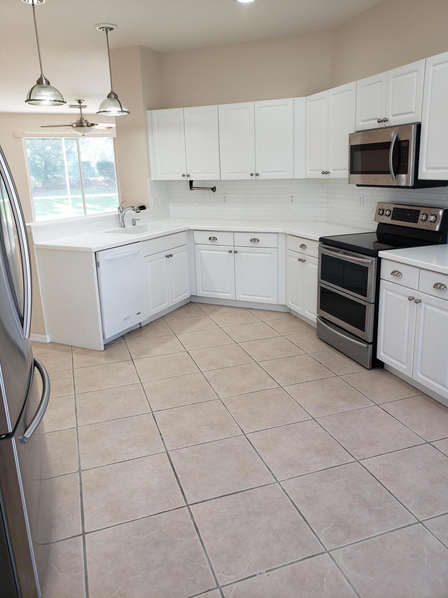 357 Southwest Coconut Key Way Port St. Lucie, FL 34986 - Photo 16 of 56 a kitchen with stainless steel appliances a sink a stove a microwave and cabinets