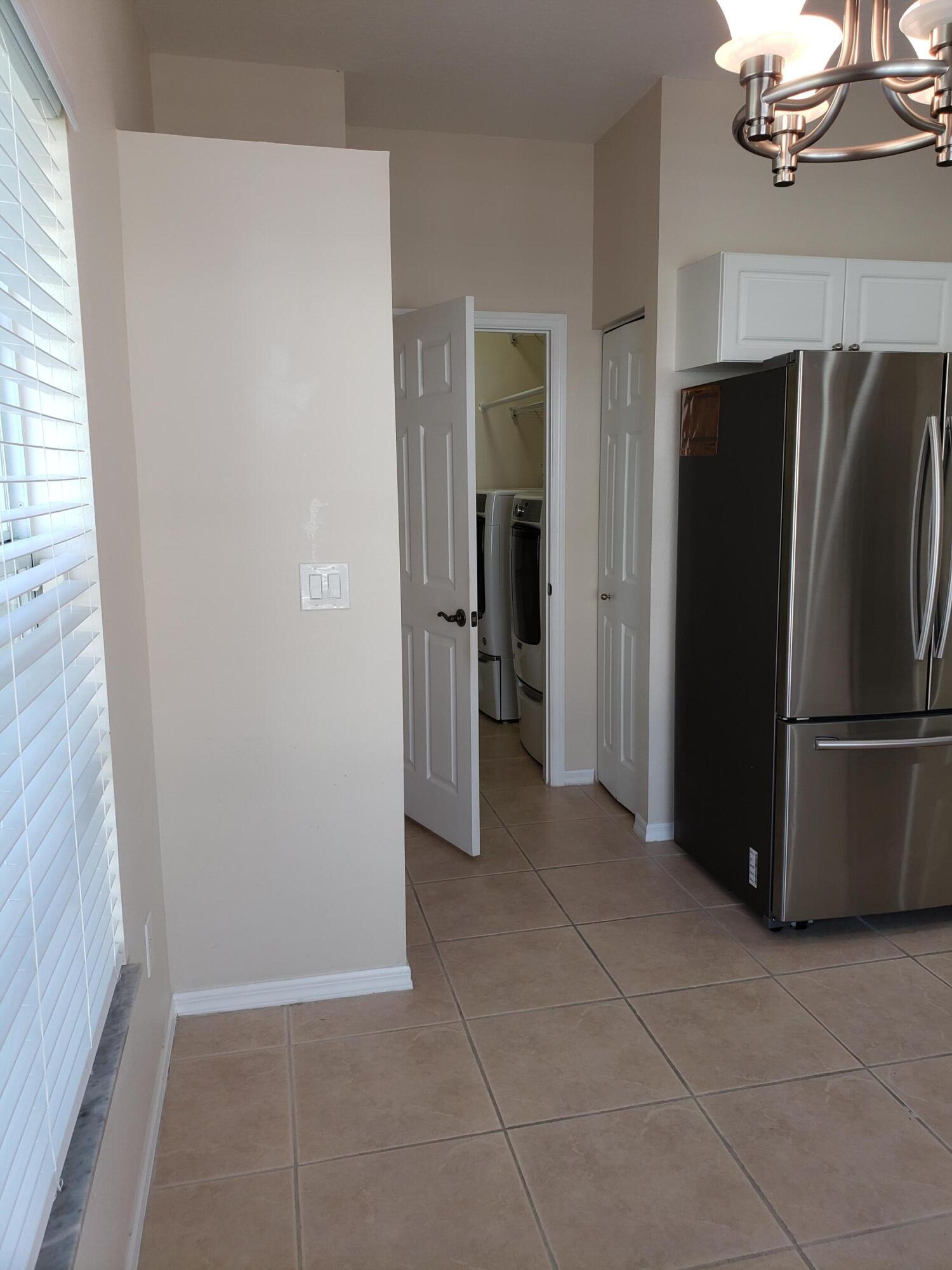 357 Southwest Coconut Key Way Port St. Lucie, FL 34986 - Photo 22 of 56 a view of a refrigerator in kitchen and an empty room with a fireplace