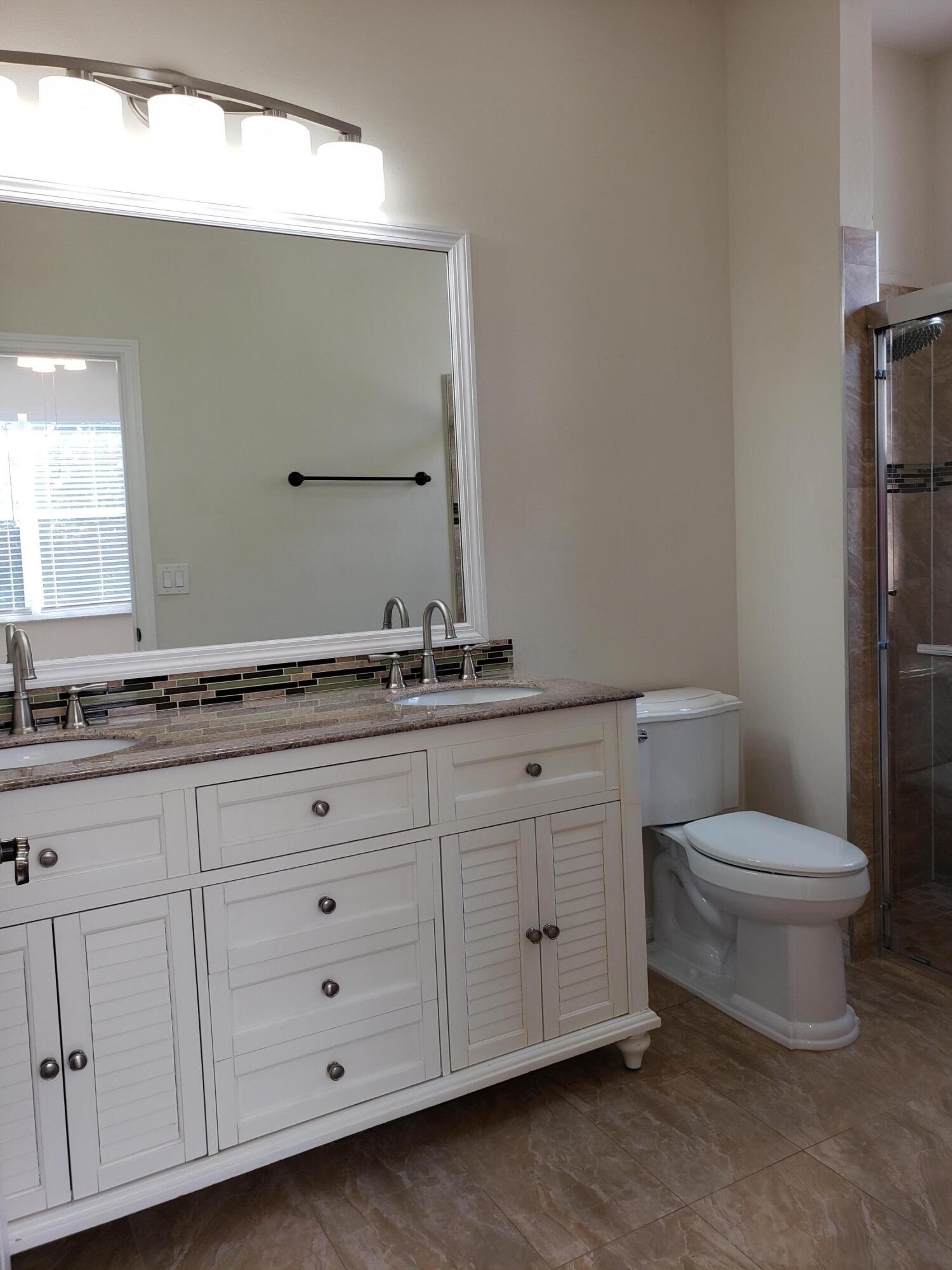 357 Southwest Coconut Key Way Port St. Lucie, FL 34986 - Photo 29 of 56 a bathroom with a granite countertop toilet sink and mirror