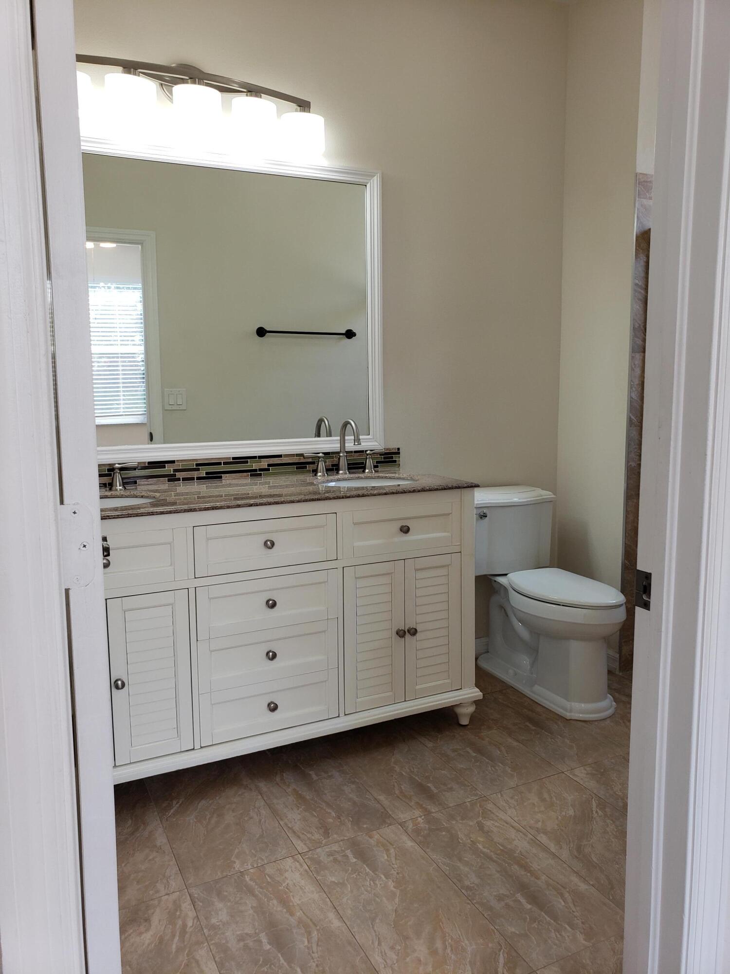 357 Southwest Coconut Key Way Port St. Lucie, FL 34986 - Photo 30 of 56 a bathroom with a granite countertop toilet sink and mirror