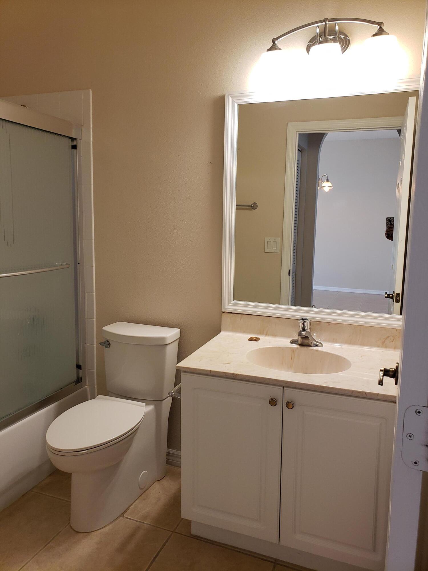357 Southwest Coconut Key Way Port St. Lucie, FL 34986 - Photo 40 of 56 a bathroom with a toilet a sink and mirror