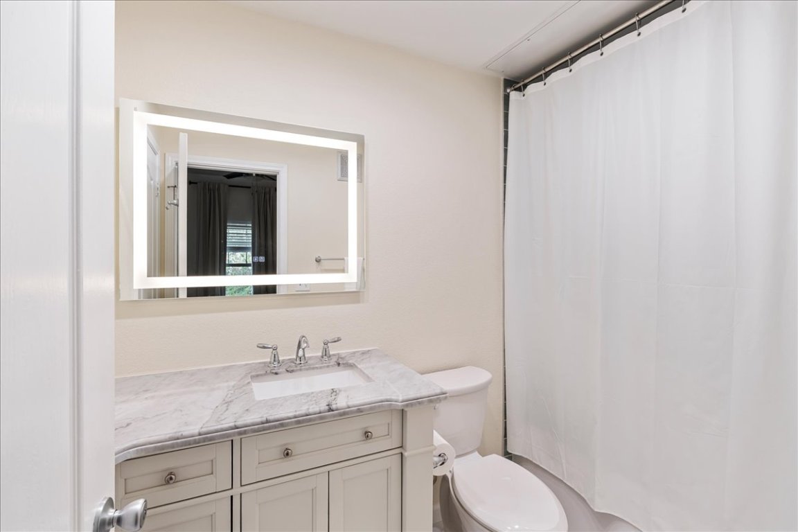 11203 Ranch Road 2222, Unit 1406 Austin, TX 78730 - Photo 27 of 37 a bathroom with a granite countertop sink toilet and mirror