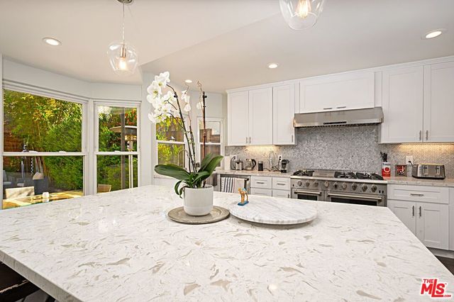 a kitchen with a stove a sink a refrigerator and a dining table with garden view